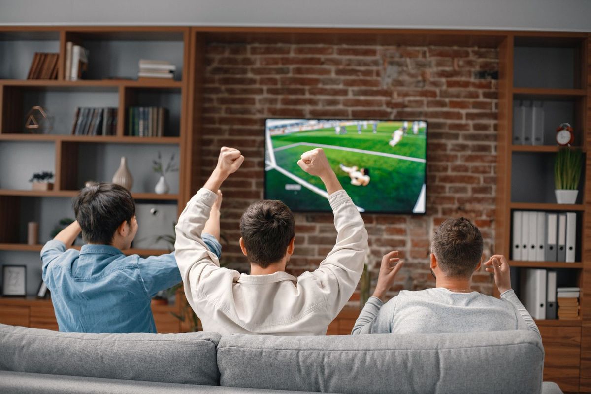 Friends cheering together as a game plays on TV